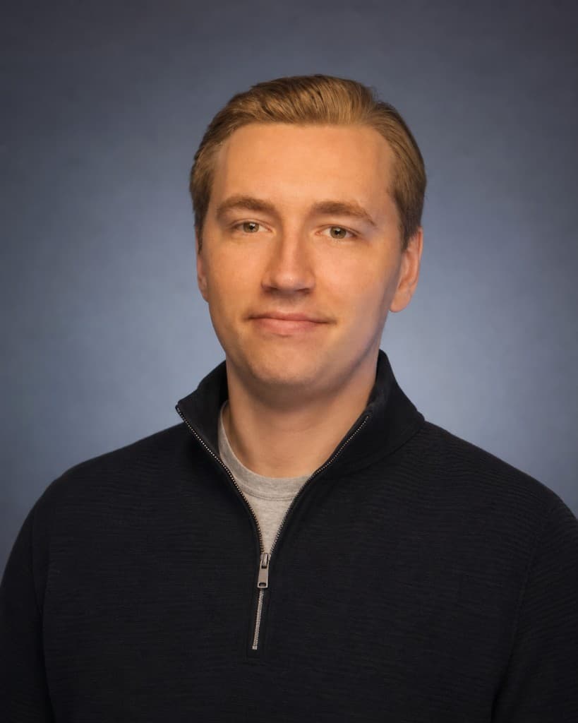 Professional headshot of Ethan, founder of EDWORX LLC, in a navy sweater against a studio backdrop.